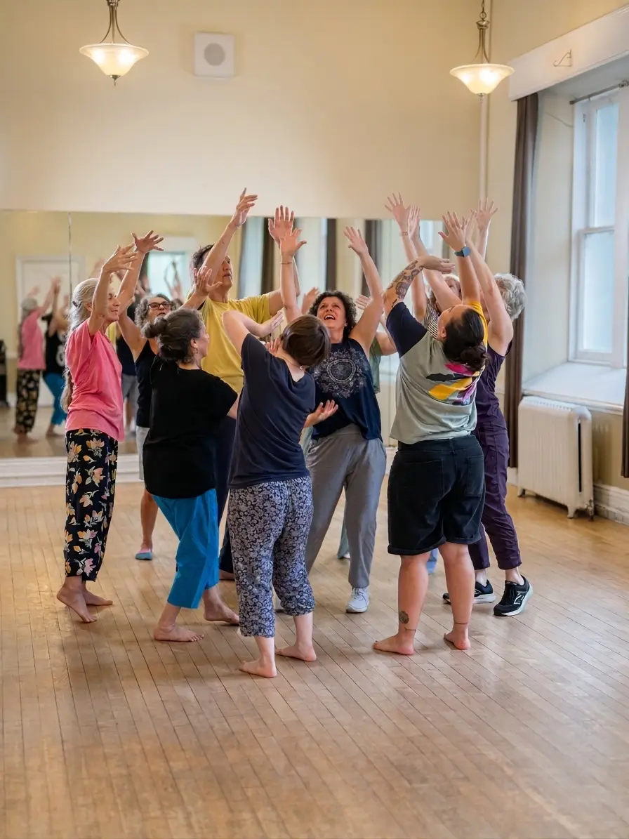 A Biodanza class in the studio, a circle of people of different ages with their arms raised, laughing