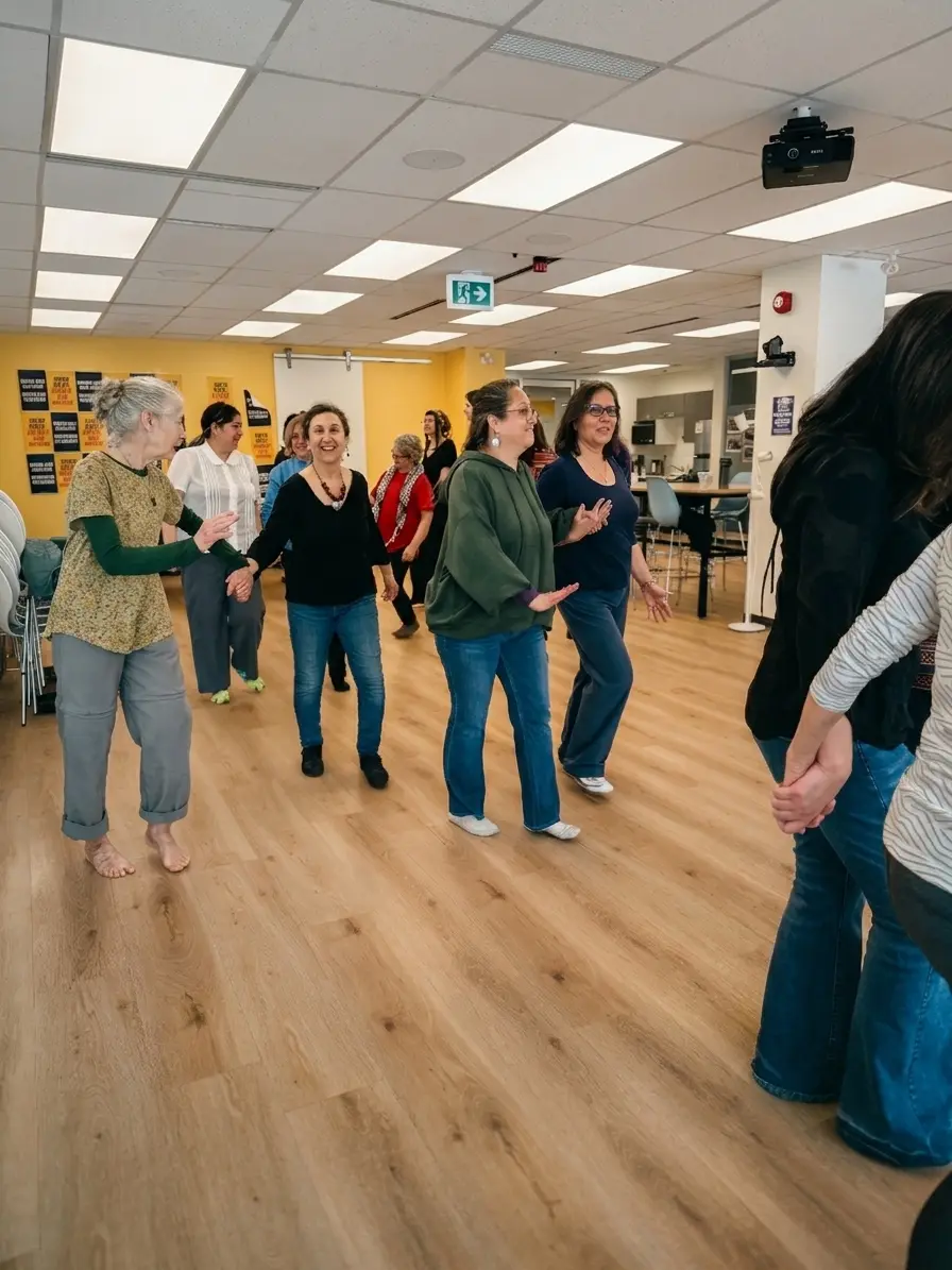 A Biodanza session running in a community room, a group holding hands and moving between the tables and chairs