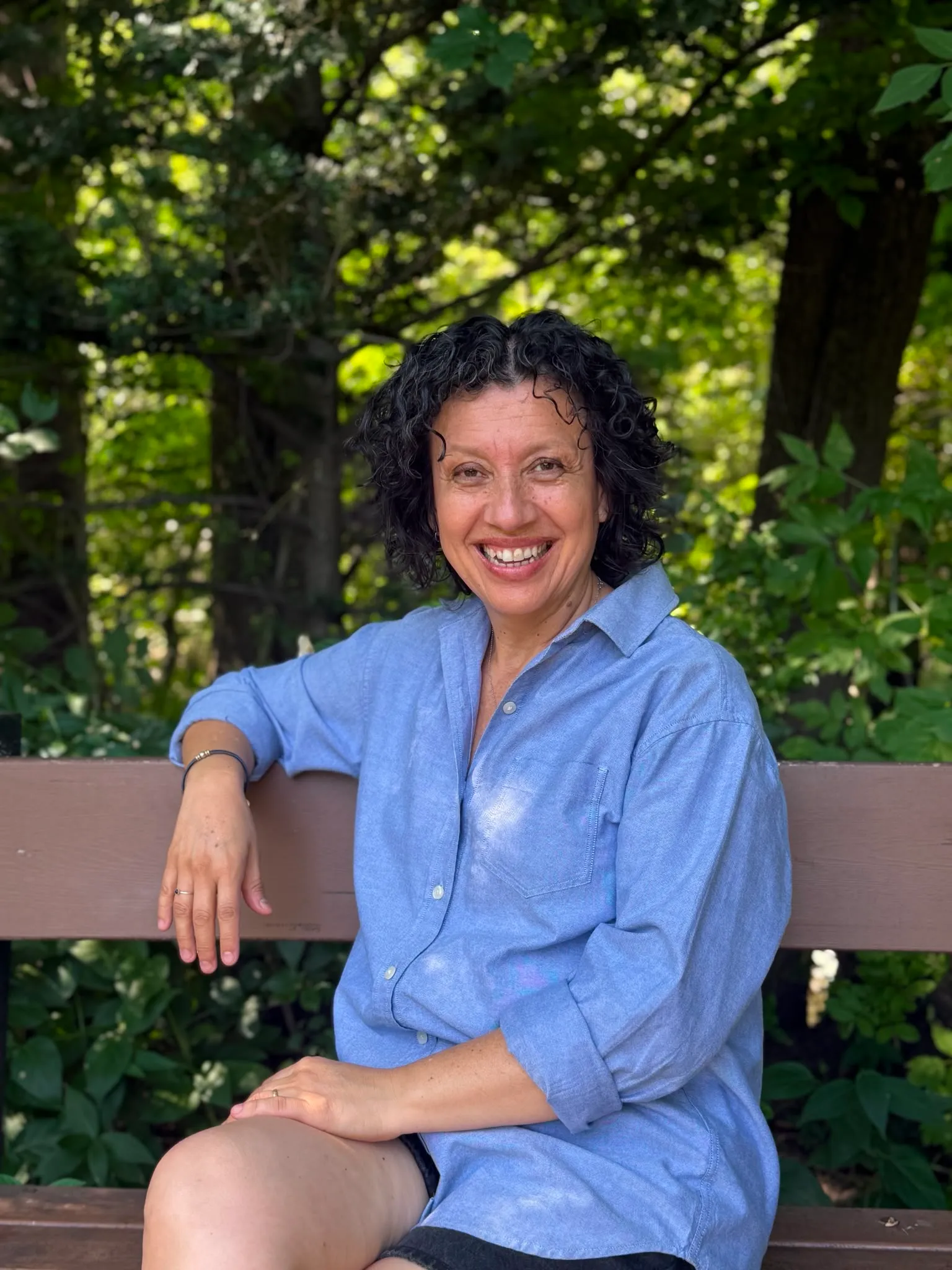 Diana Ojeda smiling, seated on a bench outdoors