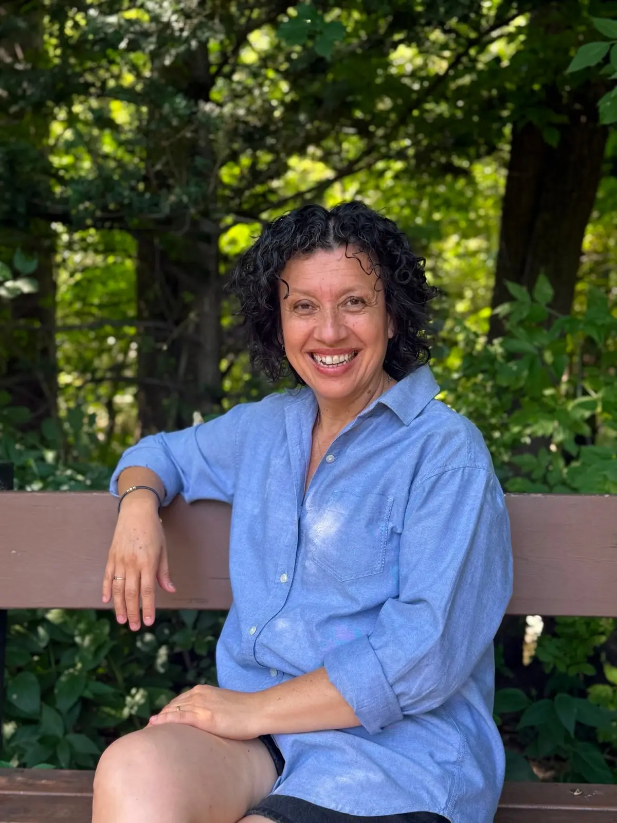 Diana standing outdoors among greenery, smiling