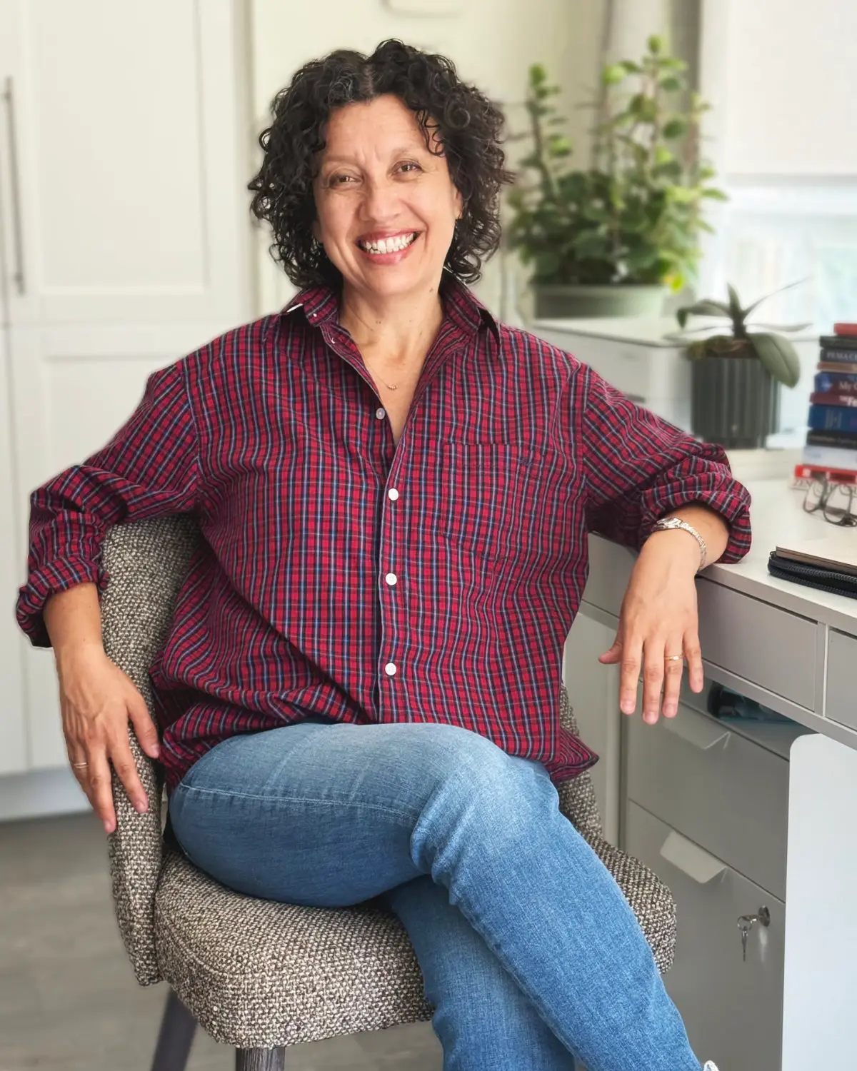 Diana Ojeda smiling, seated in the chair at her desk