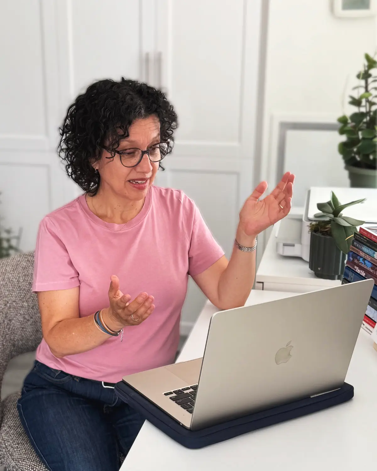 Diana talking with her hands during an online session at her desk