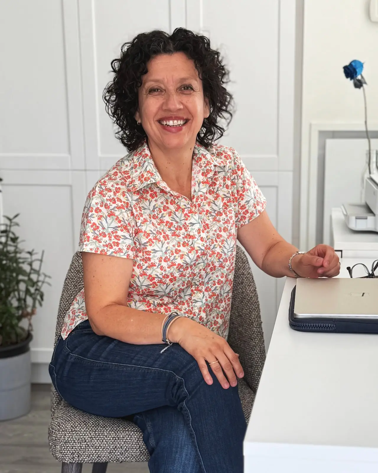 Diana sitting at her desk in a bright room, turned toward the camera and smiling